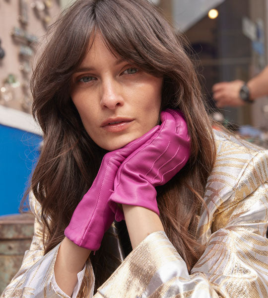 Woman wearing leather gloves in hot pink with a gold blazer in the city